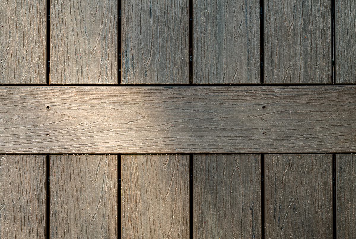 A close-up look at a Green Shield separator board breaker pattern. This intentional design crisping intersections on a Tropical Walnut deck provides a clean visual break.