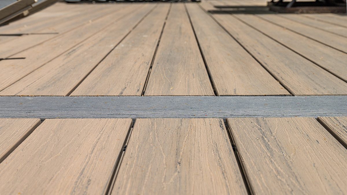 Green Shield Tigerwood composite deck boards with a Tropical Walnut composite breaker board. Beautifully contrasted color combination on a Green Shield deck showcasing variegated color and wood grain textures.