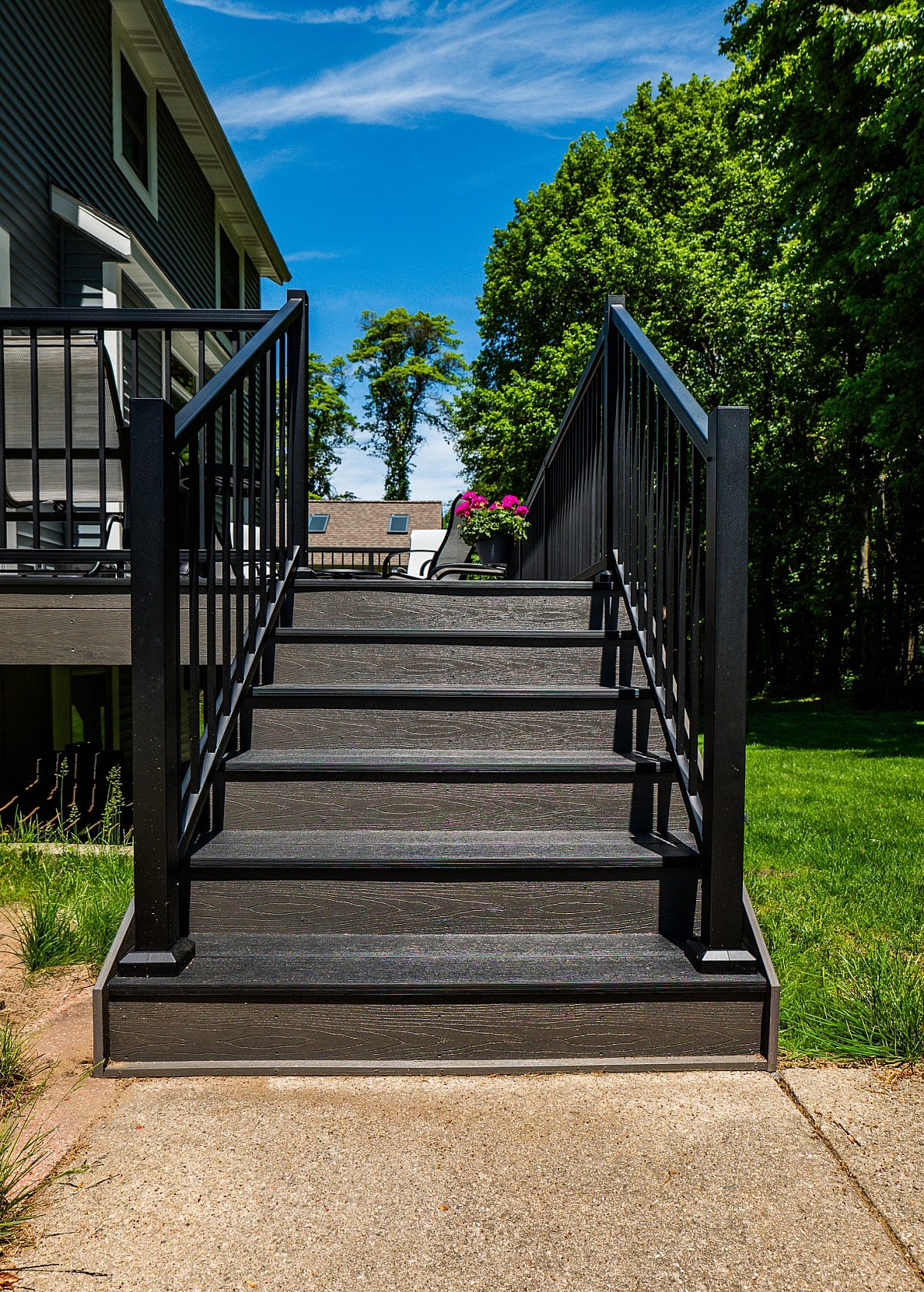 This five-step staircase provides access from the ground level to the main deck. Reversing the deck's primary color scheme, the steps feature black composite treads paired with Ash Gray compliments and black baluster railings.