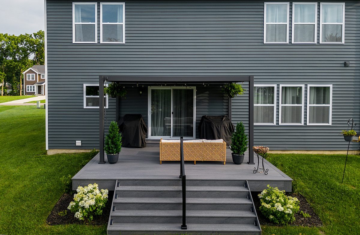 Amazon Grey decking with a contemporary steel black adjustable pergola, comfortable seating area with topiaries and ten extra-wide Green Shield steps.