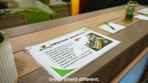 Green Shield lifetime warranty information card at the home show booth in 2026.